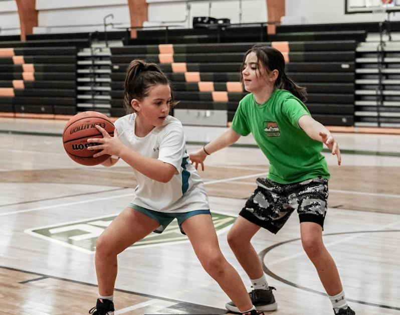 Two female basketball players practice defending the ball
