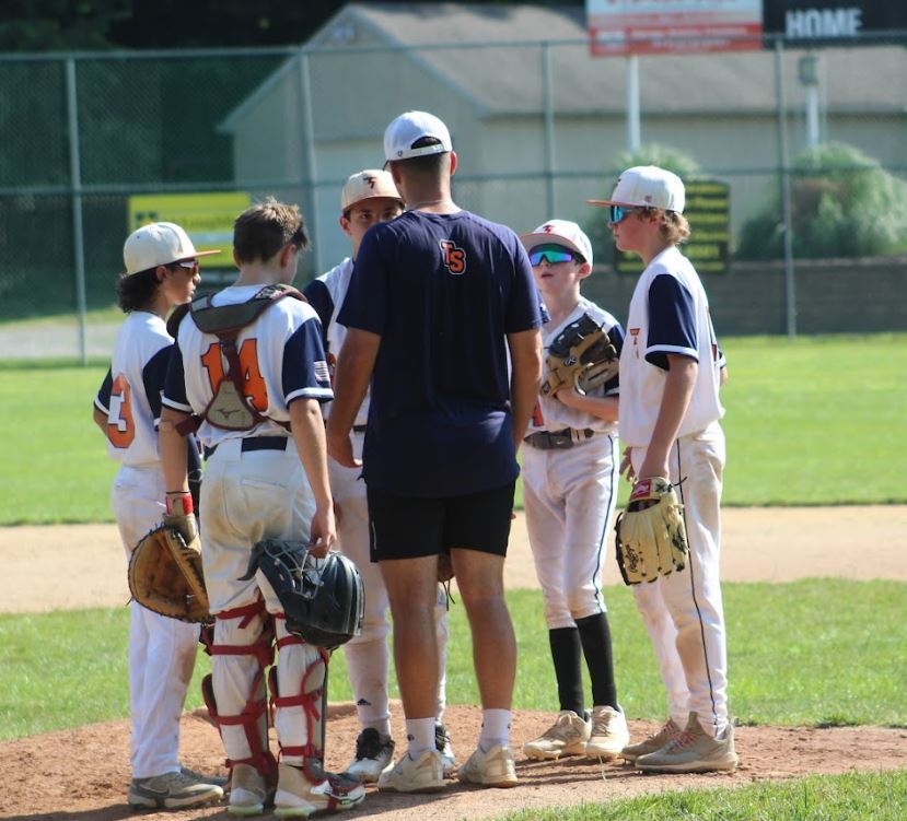 A coach talks with a youth sports baseball team