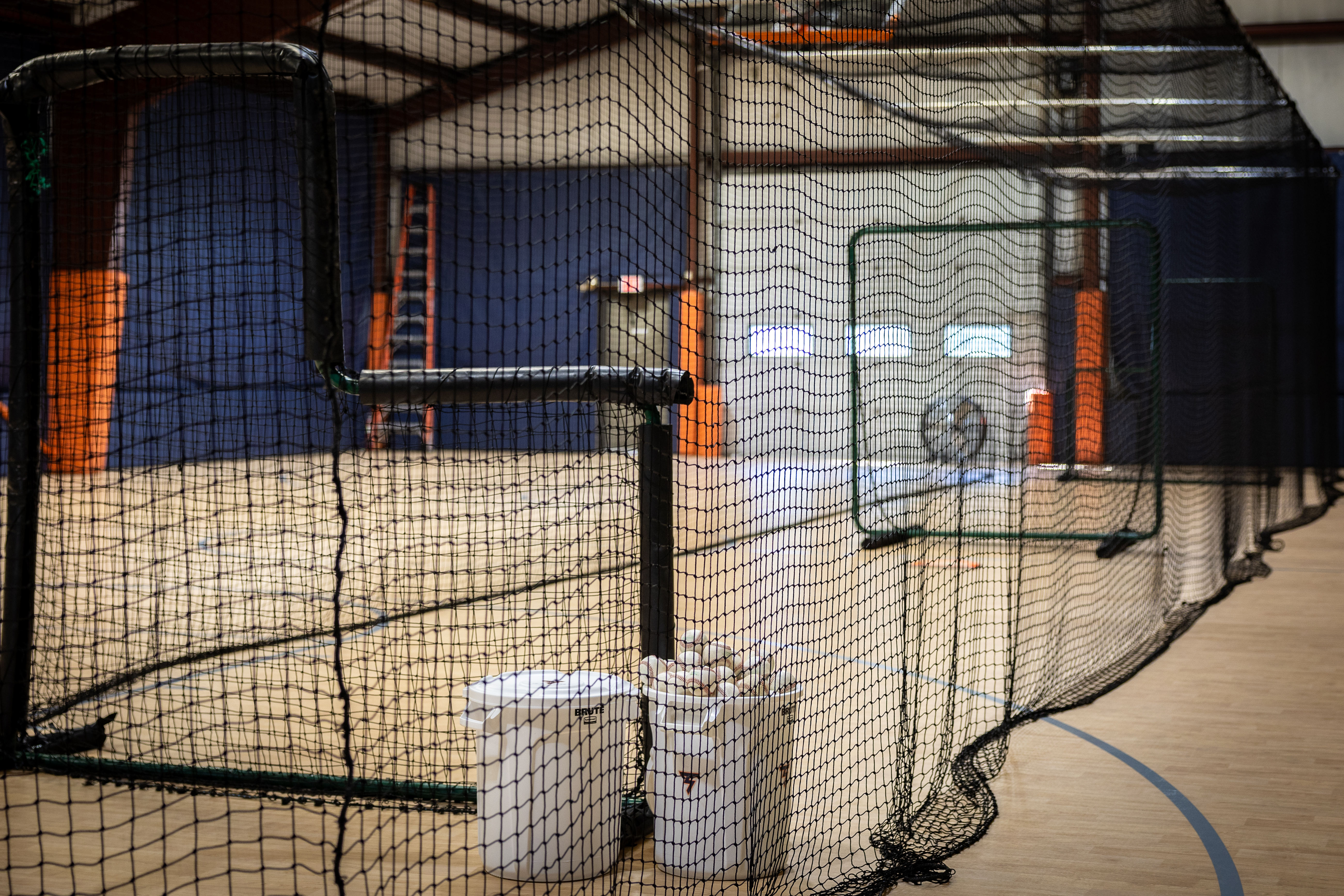 batting nets over the basketball court. batting cages and buckets of baseballs