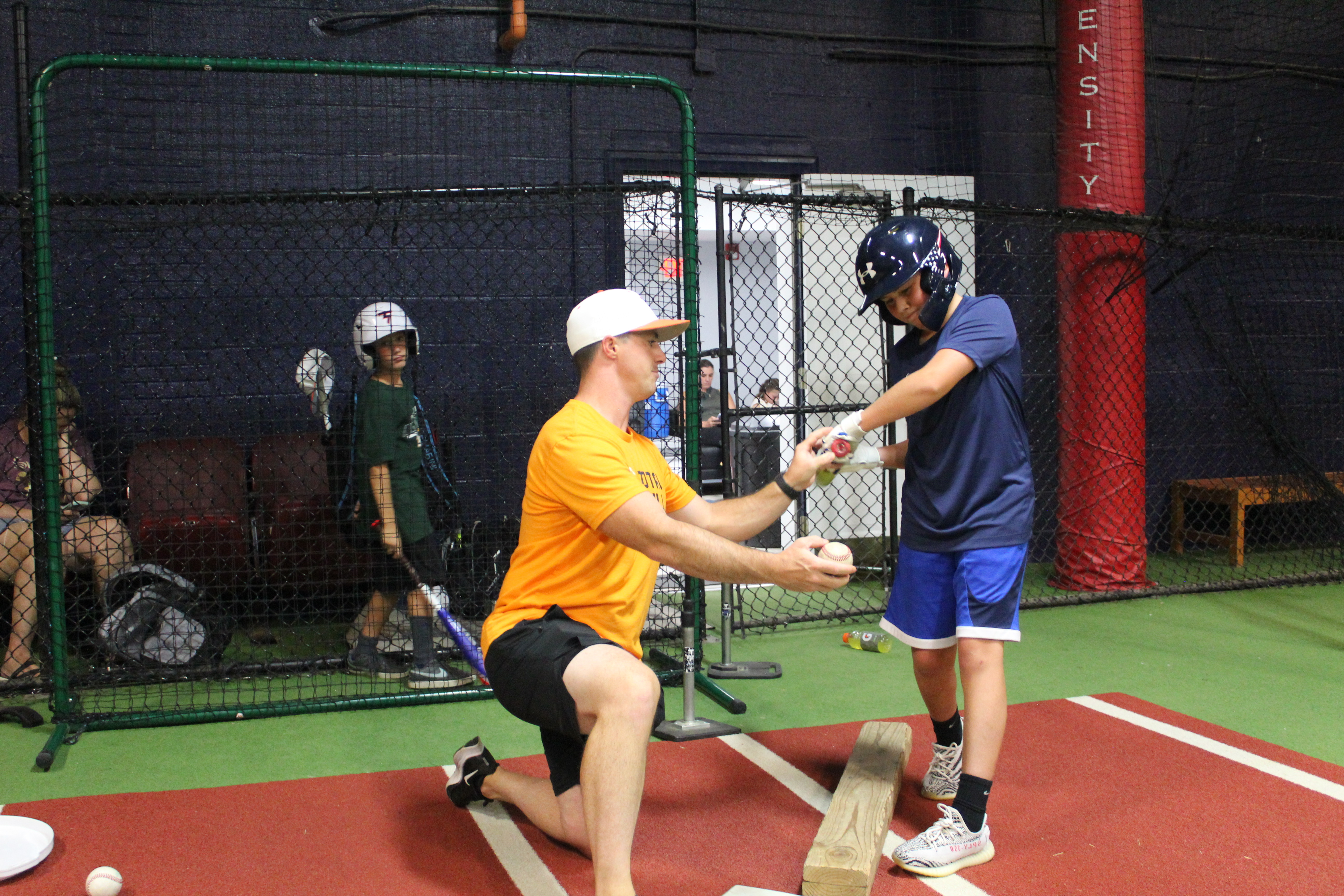 A youth sports coach demonstrates how to hit a ball